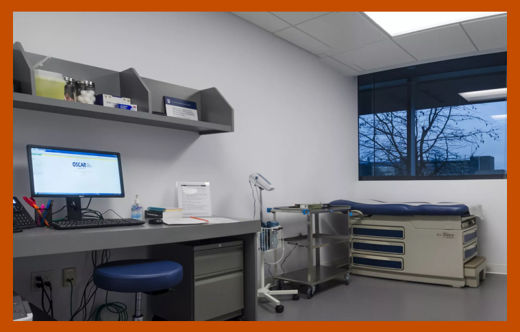 An empty clinic room with the OSCAR EMR visible on a monitor.
